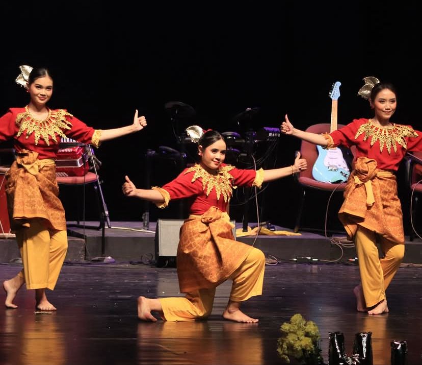 Tiga penari perempuan berbusana merah dan kuning membawakan Tari Persembahan di atas panggung