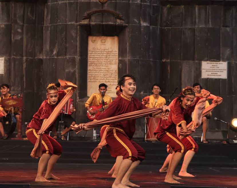 Penari berbusana merah membawakan tari tradisi Melayu dengan iringan musik di panggung
